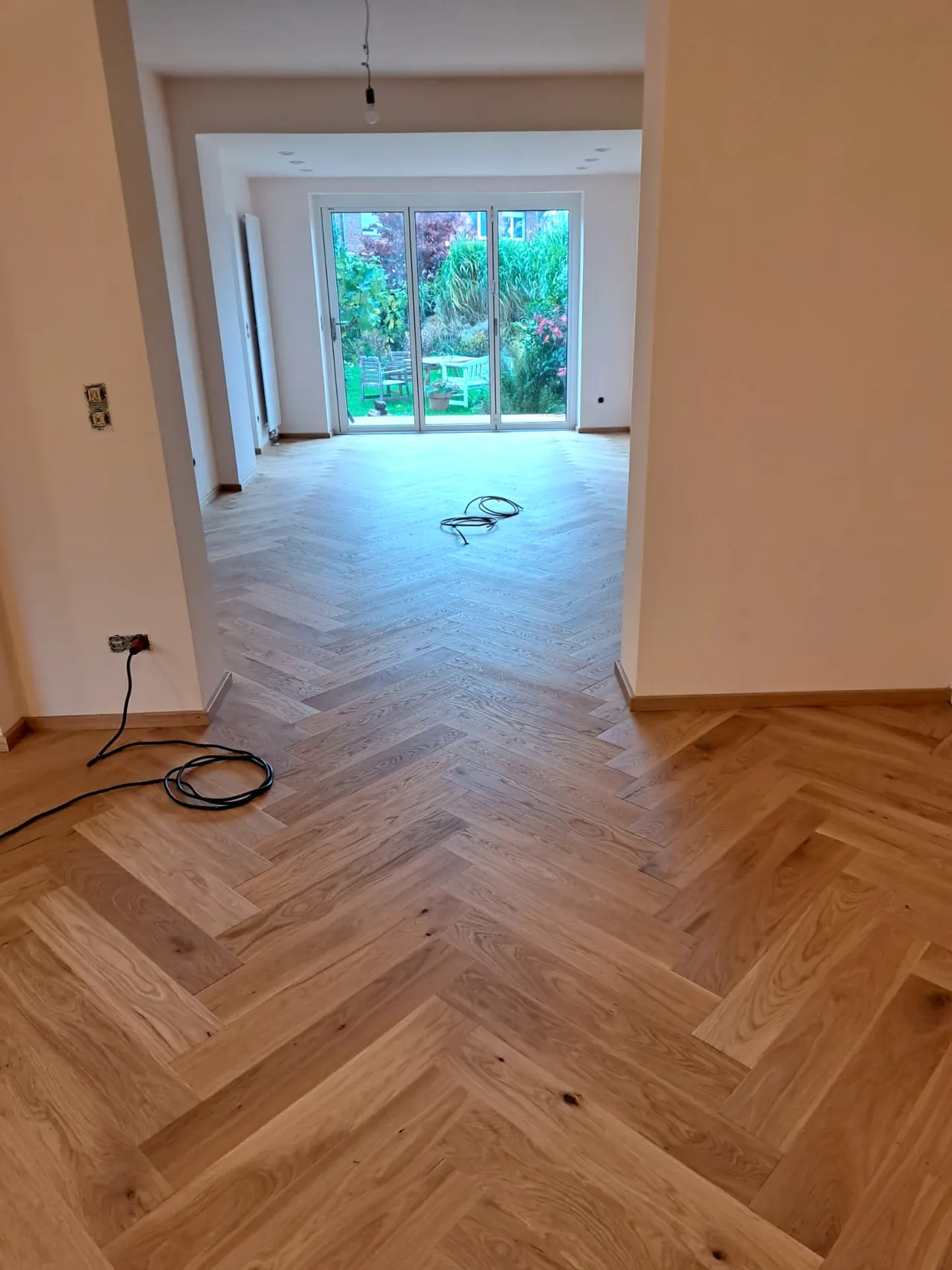 Wohnzimmer mit frisch verlegtem Fischgrätparkett aus Eiche und Blick in den Garten, Schreinerei Da Cunha Mönchengladbach