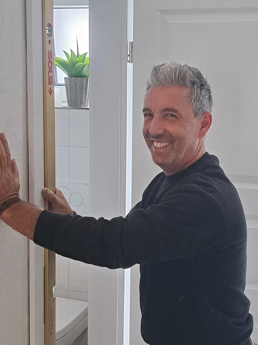 Manuel da Cunha, Inhaber der Schreinerei Da Cunha in Mönchengladbach, prüft eine Türzarge mit der Wasserwaage